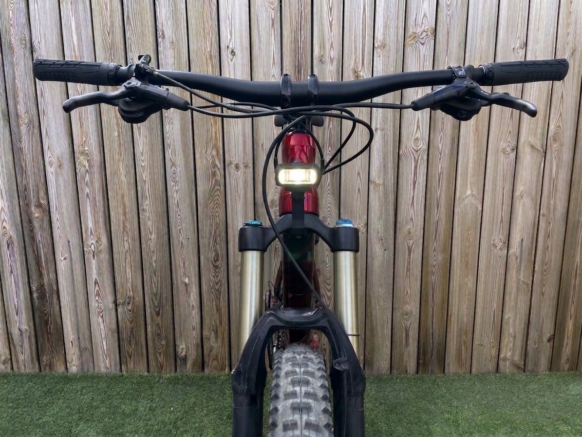 Mountain bike at dusk — two front lights, arrow pointing to the lower centered optimal position